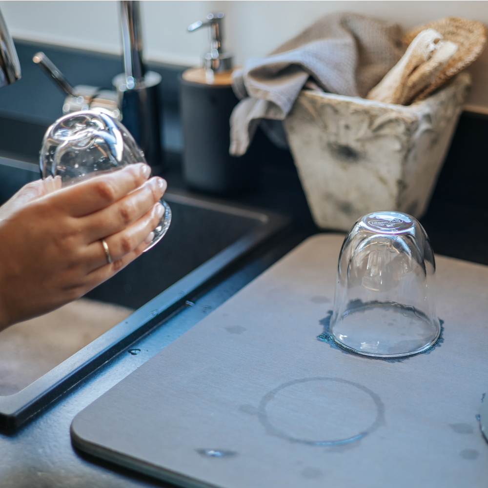 A glass drying upside down on a diatomite dry stone beside a kitchen sink