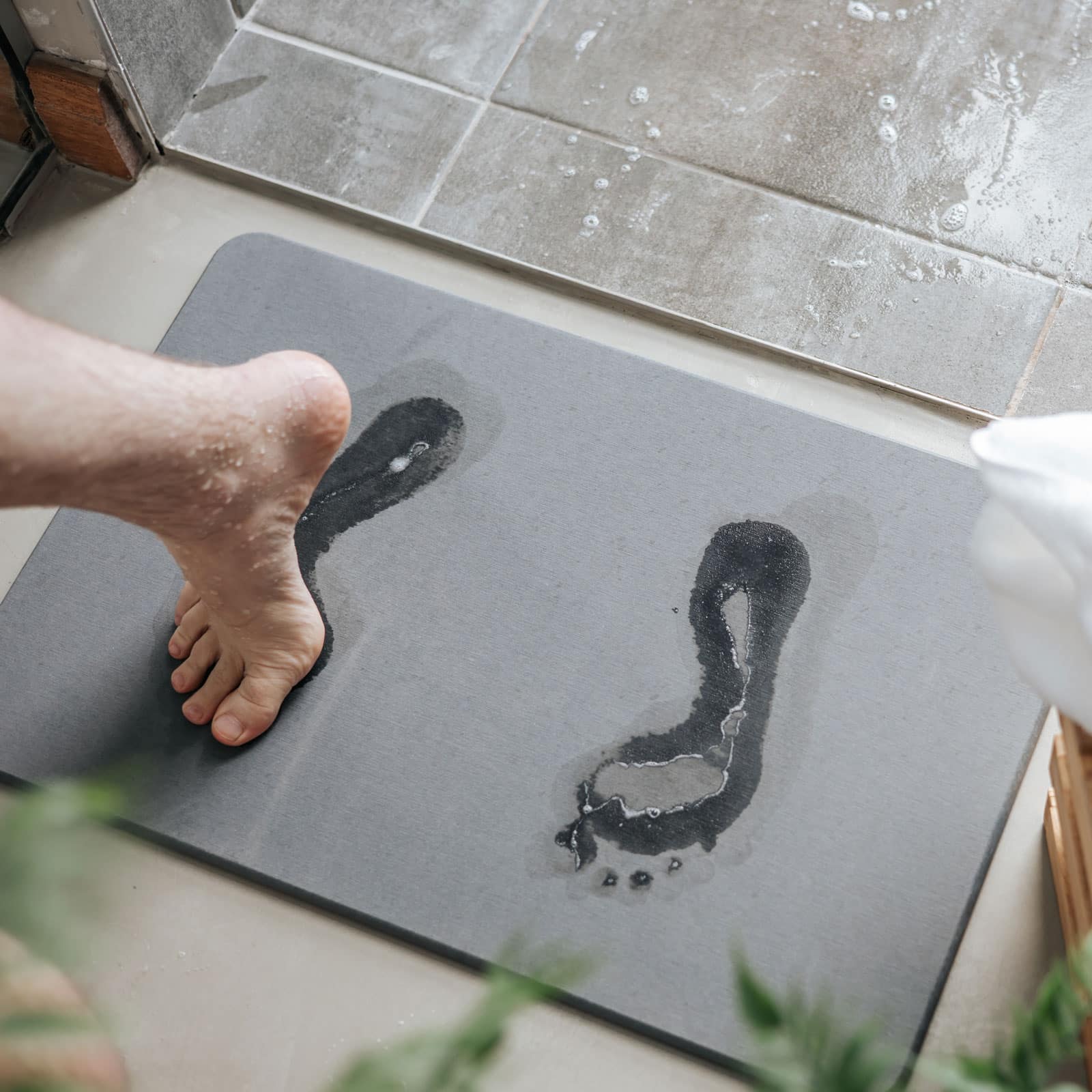 A wet foot stepping onto a diatomite bath stone, damp footprints absorbed into the surface